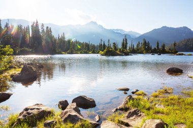 Kanada 'daki dağ gölünün sakin sularındaki kayaların yansımasıyla sakin bir manzara..