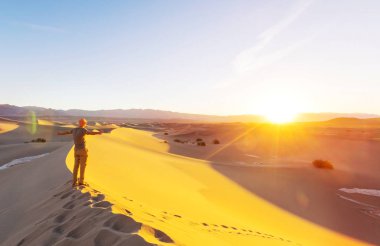 Kum çölünde bir yürüyüşçü. Gün doğumu zamanı.