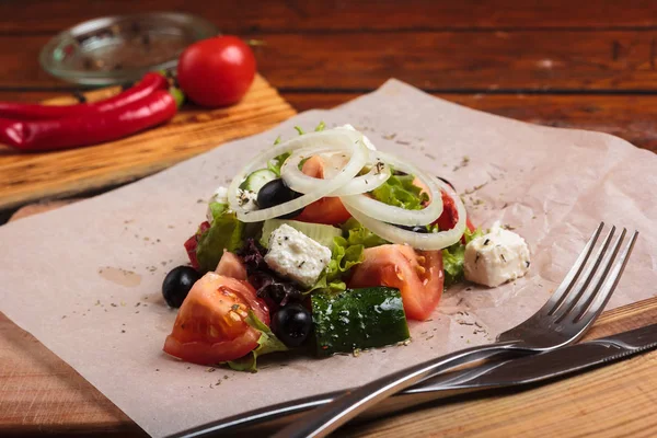 Greek salad served on paper with ingredients — Stock Photo, Image