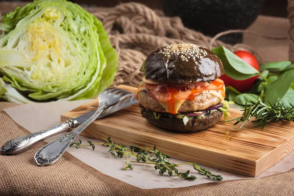 Trendy hamburger lucido con manzo in panino nero Immagini Stock Royalty Free