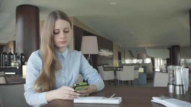 Meisje controleren en praten op een telefoon bij het raam — Stockvideo