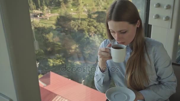 Chica beber té por la ventana del restaurante de moda — Vídeo de stock