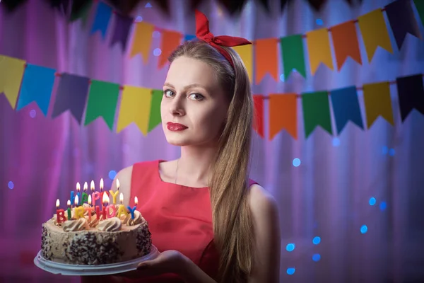 Hermosa joven vintage pin up chica de estilo de pie en colorida escena iluminada celebración de la torta con velas . —  Fotos de Stock