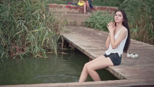 Schöne junge Frau ruht barfuß auf kleiner Seebrücke — Stockvideo