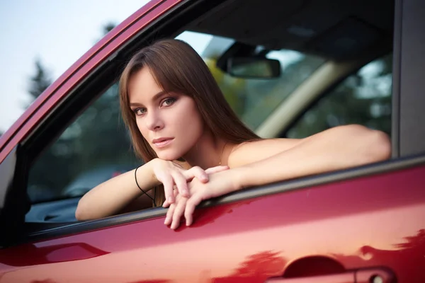 Hermosa chica sentada detrás del volante mirando hacia fuera — Foto de Stock