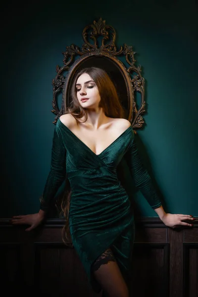 Beautiful woman with long hair sensual greed dress and stockings studio photoshoot Stock Photo