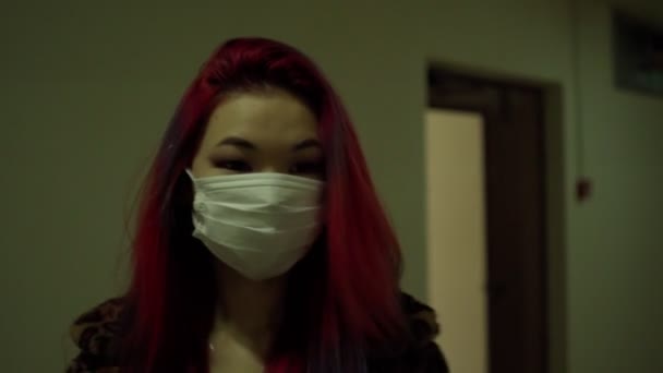Schöne junge asiatische Mädchen in medizinische Maske Kleidung gehen düsteren dunklen Flur — Stockvideo