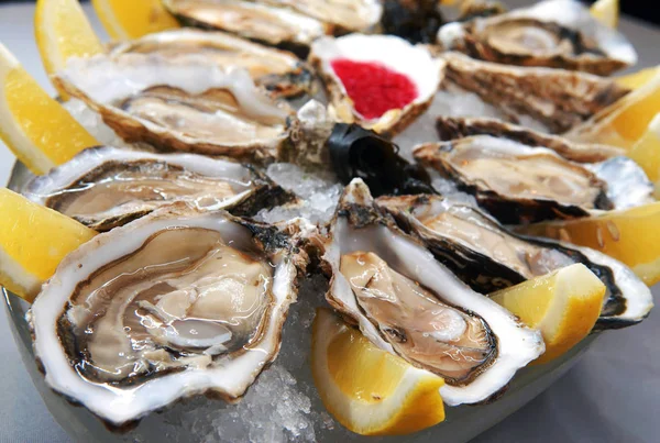 Schotel van verse oesters met saus en citroen geserveerd op een marmeren va — Stockfoto