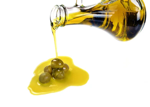 Выливание оливкового масла из бутылки в зеленые оливки — стоковое фото