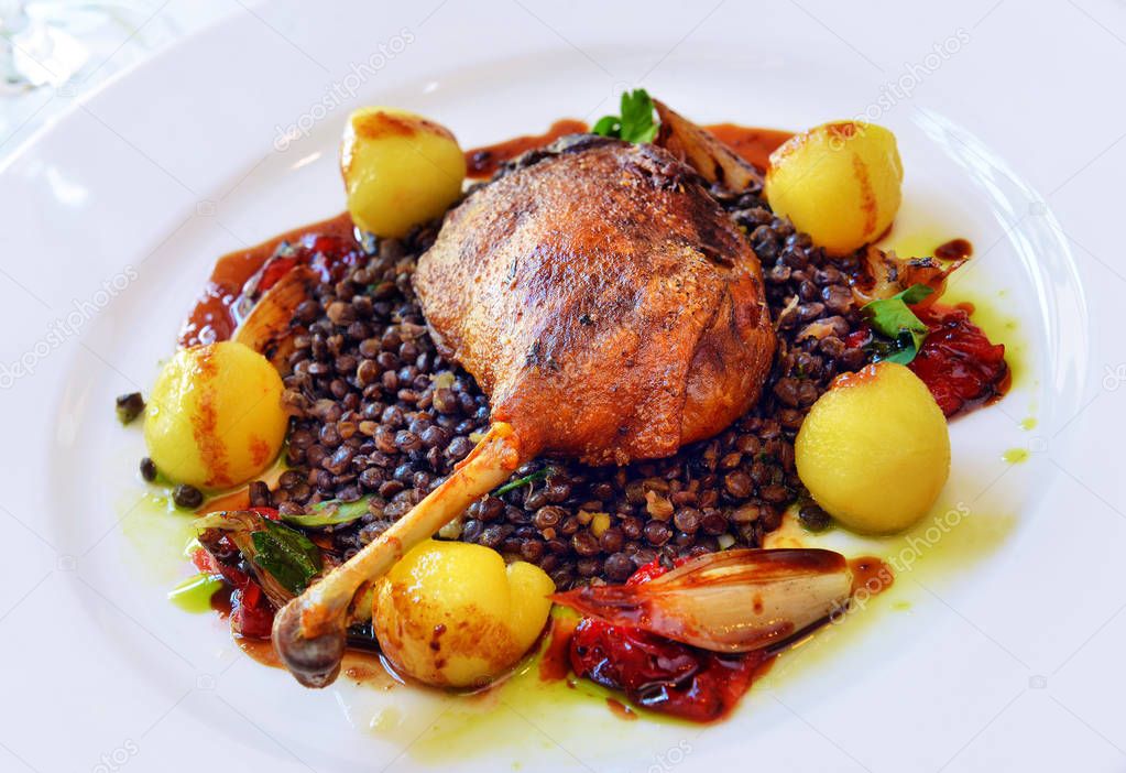 duck leg with lentils in a white plate