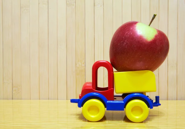 Toy plastic car with red apple — Stockfoto