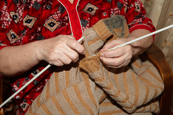 Old woman and knitting sweater