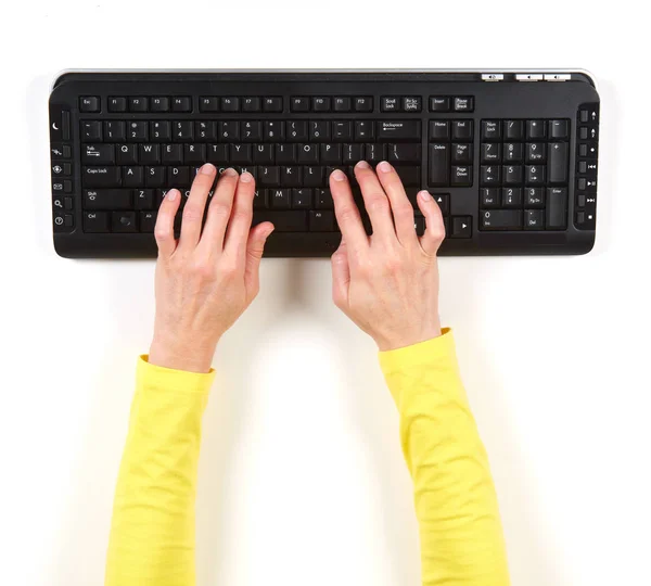 Handen in gele jas en zwarte toetsenbord — Stockfoto