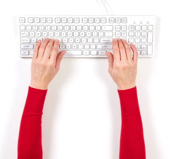 Mãos em casaco vermelho e teclado branco — Fotografia de Stock