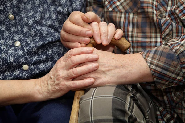 Руки пожилой пары с тростью — стоковое фото