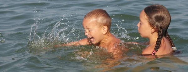 Malý chlapec a dívka hraje v moři — Stock fotografie