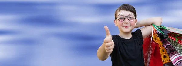 Kleines Mädchen mit Einkaufstaschen auf blauem Hintergrund — Stockfoto