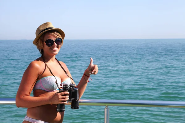 Mujer joven con prismáticos y el mar — Foto de Stock