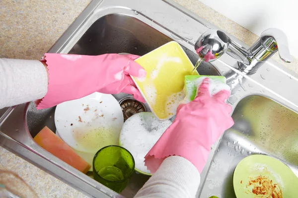 Mãos lavando pratos com água corrente da torneira — Fotografia de Stock