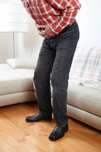 Unhappy man suffering from belly-ache at home