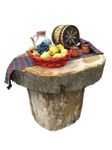 Mesa feita de troncos com cesta de frutas e barril de vinho — Fotografia de Stock