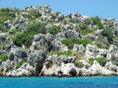 Mavi gökyüzü üzerinde yüksek kaya dağları ve deniz