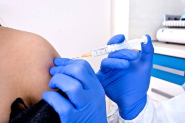 Koruyucu kıyafetli doktor hastaya aşı veriyor. Coronavirüs salgını. Covid-19 konsepti.