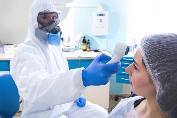 Lekarz Mundurze Ochronnym Masce Sprawdza Temperaturę Młodej Pacjentki Epidemia Koronawirusa — Zdjęcie stockowe