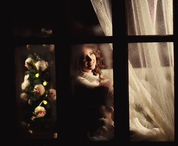 Счастливая жизнерадостная девушка, выглядывающая в замерзшее окно — стоковое фото