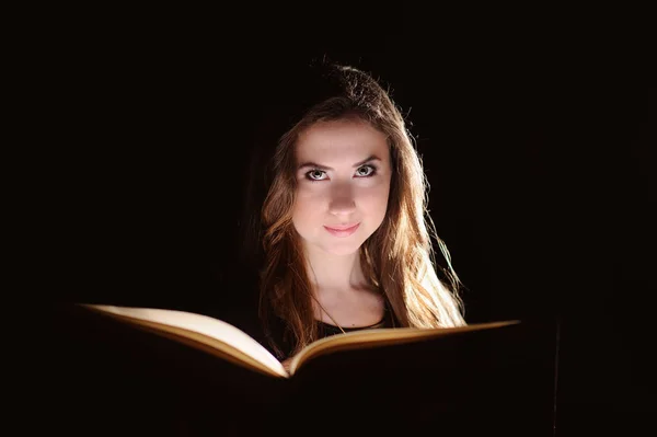 Retrato de jovem estudante lendo um livro sobre fundo preto — Fotografia de Stock