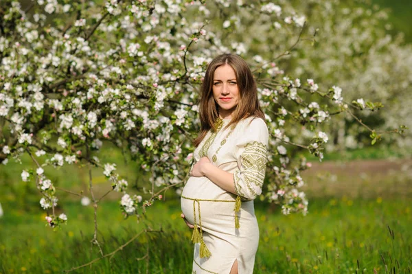 Těhotná žena v rozkvetlé zahradě — Stock fotografie