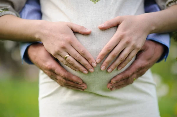 Pregnant woman with husband  in blooming garden — Stock Photo, Image