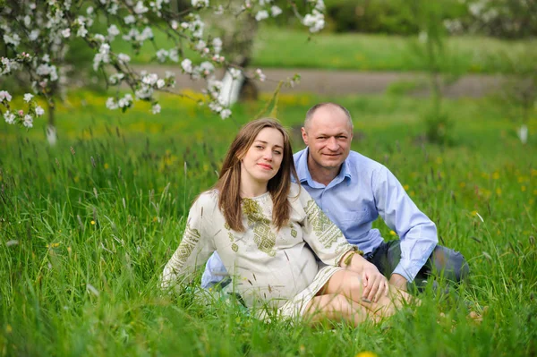 Těhotná žena s manželem v rozkvetlé zahradě — Stock fotografie