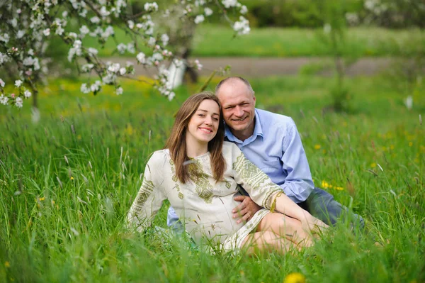 Pregnant woman with husband  in blooming garden — Stock Photo, Image