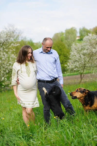 Mulher grávida com marido no jardim florescente — Fotografia de Stock