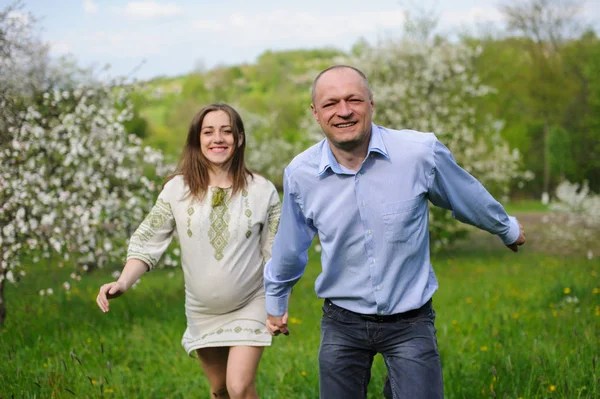 Těhotná žena s manželem v rozkvetlé zahradě — Stock fotografie