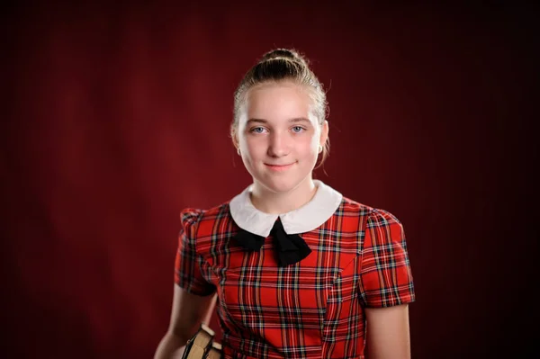 Sevimli kız öğrenci kırmızı arka plan üzerinde gülümseyen — Stok fotoğraf