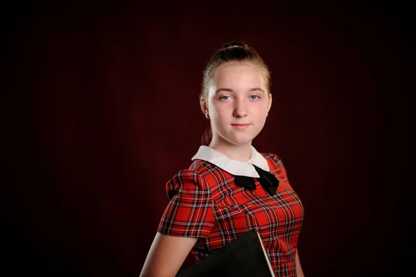 Cute smiling schoolgirl on the red background — Stock Photo, Image