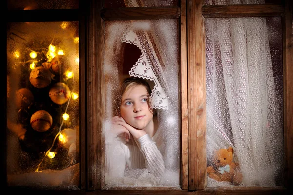 Girl looking through the winter window — Stock Photo, Image