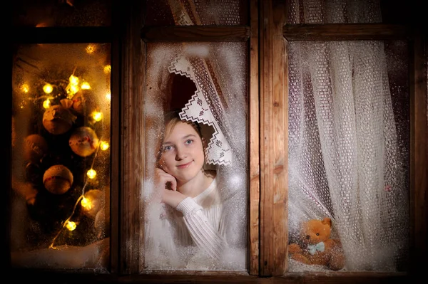 Ragazza guardando attraverso la finestra invernale — Foto Stock