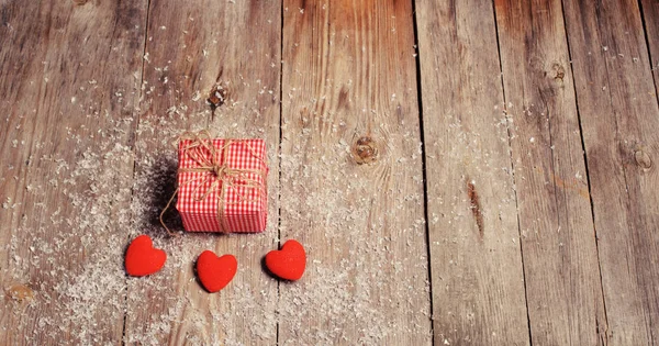 Heart on a wooden background with snow and gift box — Stock Photo, Image