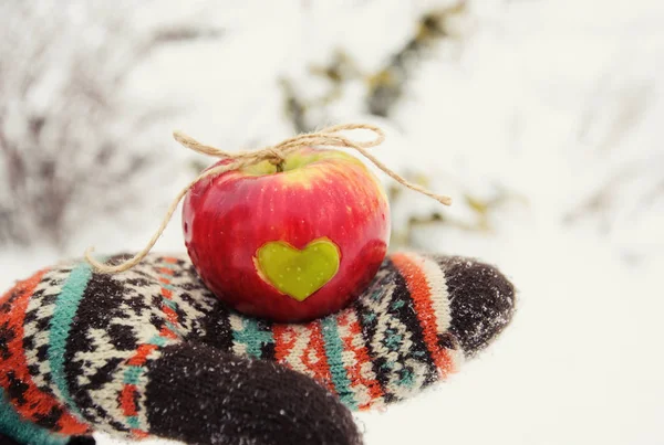 Manzana con corazón en las manos en invierno — Foto de Stock
