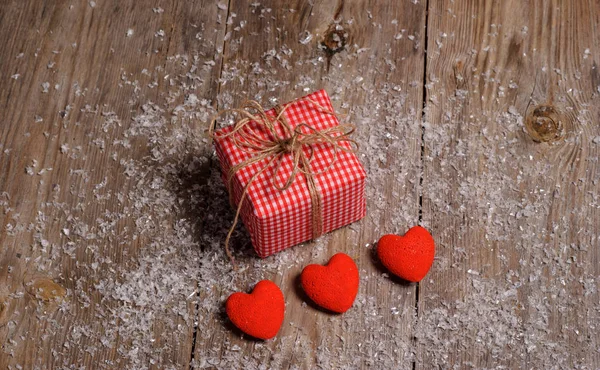 Corazón sobre fondo de madera con nieve y caja regalo — Foto de Stock