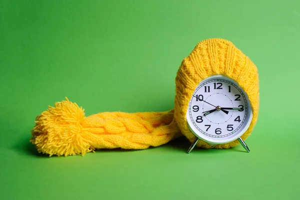 Alarm clock in yellow hat on the green background — Stock Photo, Image