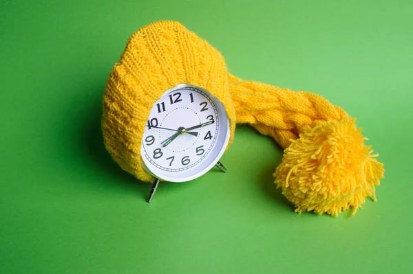 Relógio despertador em chapéu amarelo no fundo verde — Fotografia de Stock