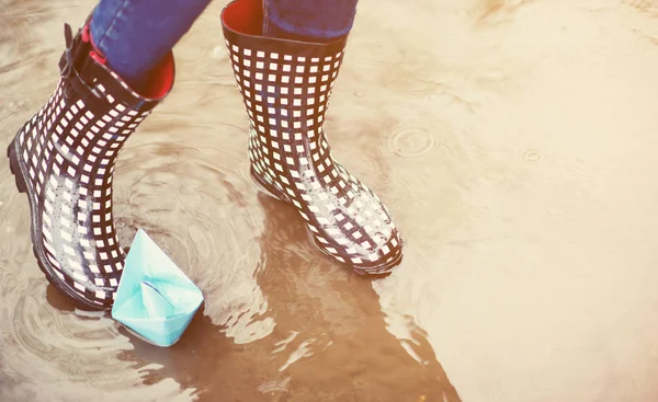 Girl playing with paper boats in puddle — Stock Photo, Image