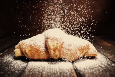 kruvasan ahşap masa üzerine pudra şekeri ile