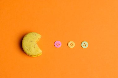 Tatlı ve renkli Fransızca macaroons veya retro oyun pacman gibi turuncu zemin üzerine macaron