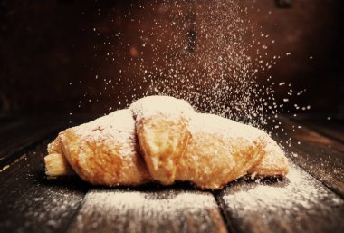 kruvasan düşen pudra şekeri ile ahşap masa