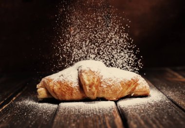 kruvasan düşen pudra şekeri ile ahşap masa